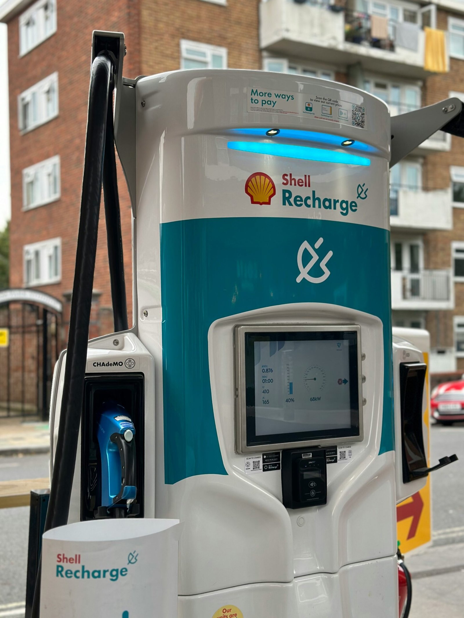 A white and blue gas pump sitting on the side of a road